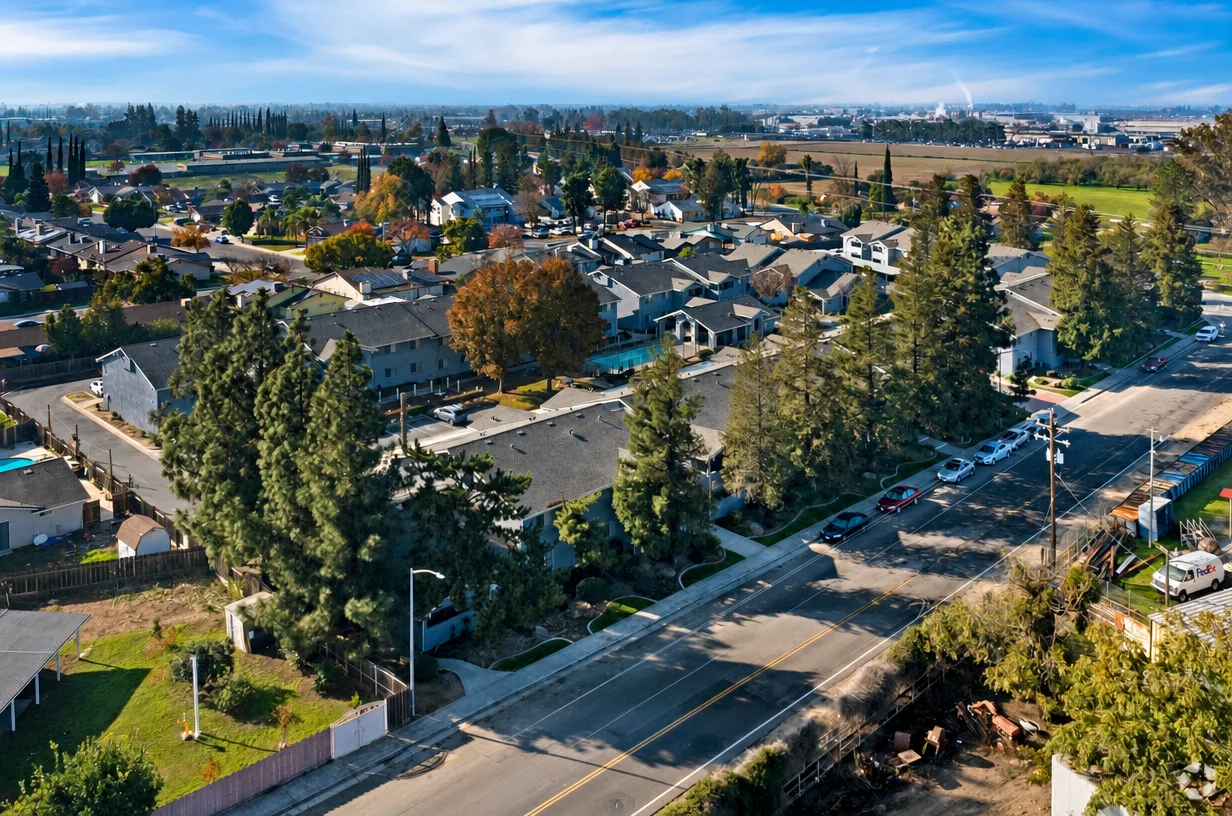 Aerial view of an apartment complex with a swimming pool in a tree-lined neighborhood in Livingston, California