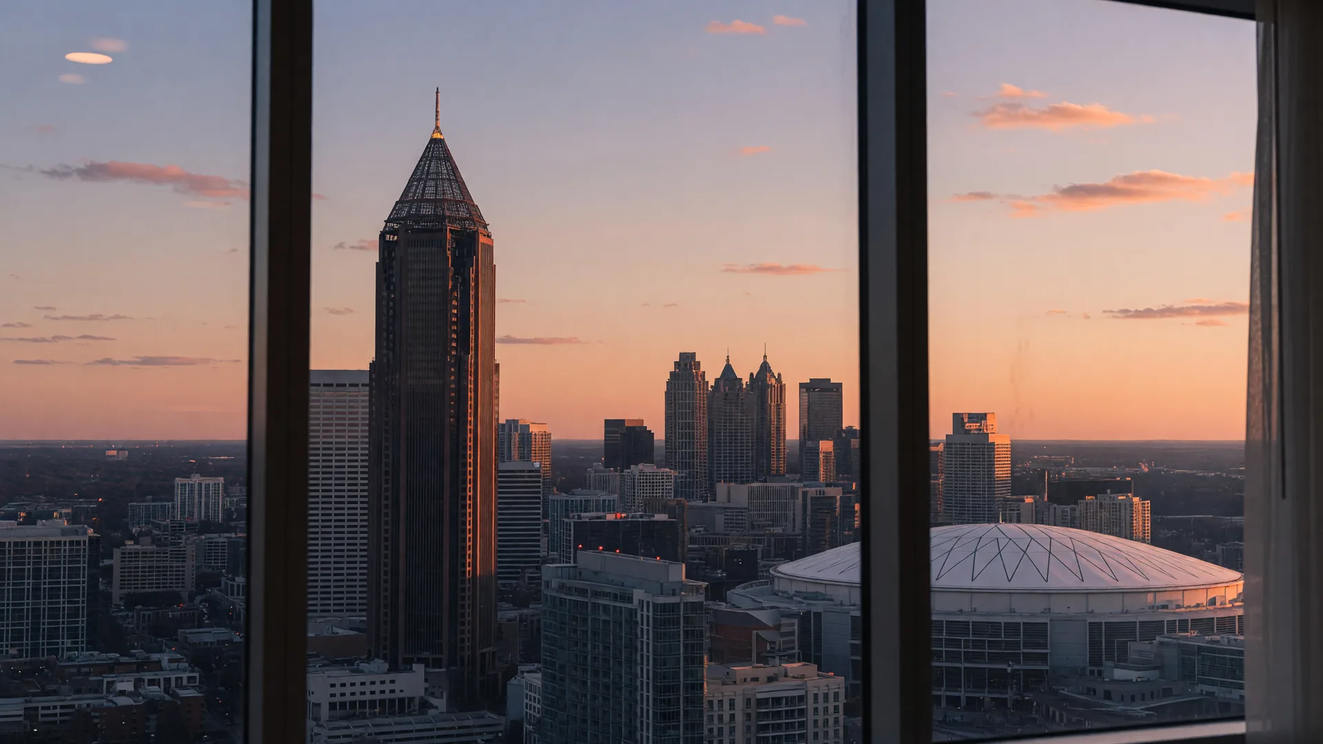 Atlanta skyline at golden hour viewed from a high rise window with warm sunset lighting