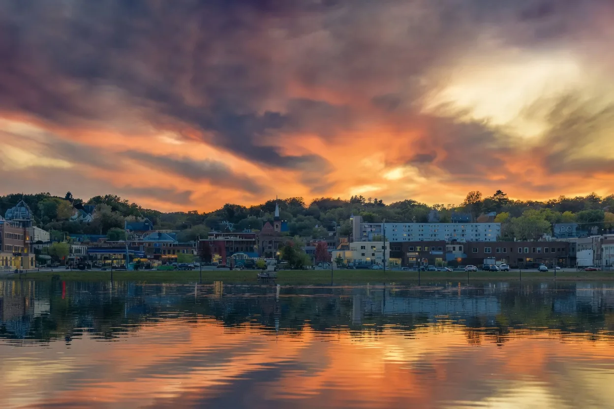 Scenic waterfront town skyline under a vibrant orange and purple sunset