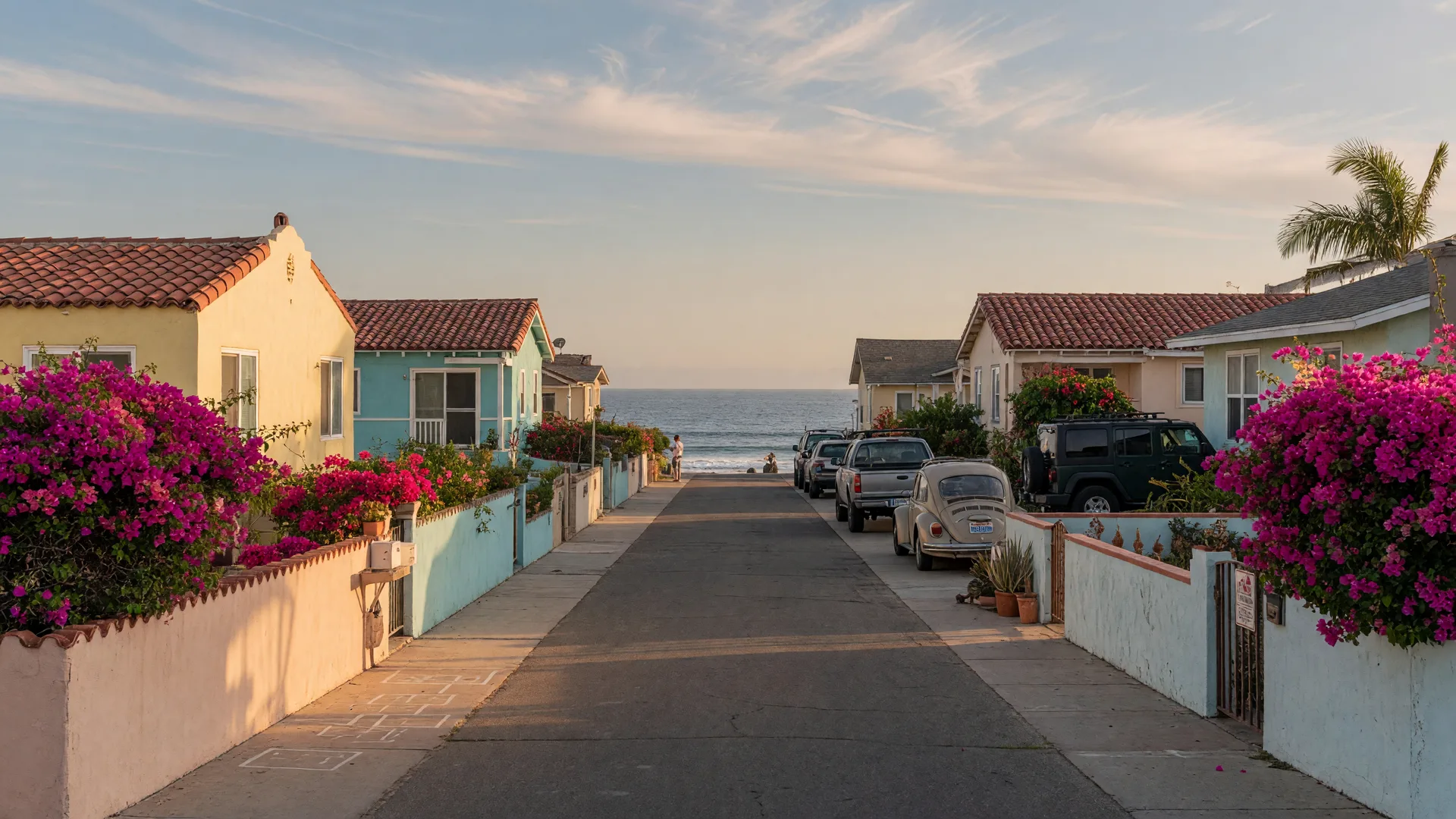 Quiet beach-town street in coastal San Diego with garden walls, bougainvillea, and Spanish-style cottages at golden-hour light