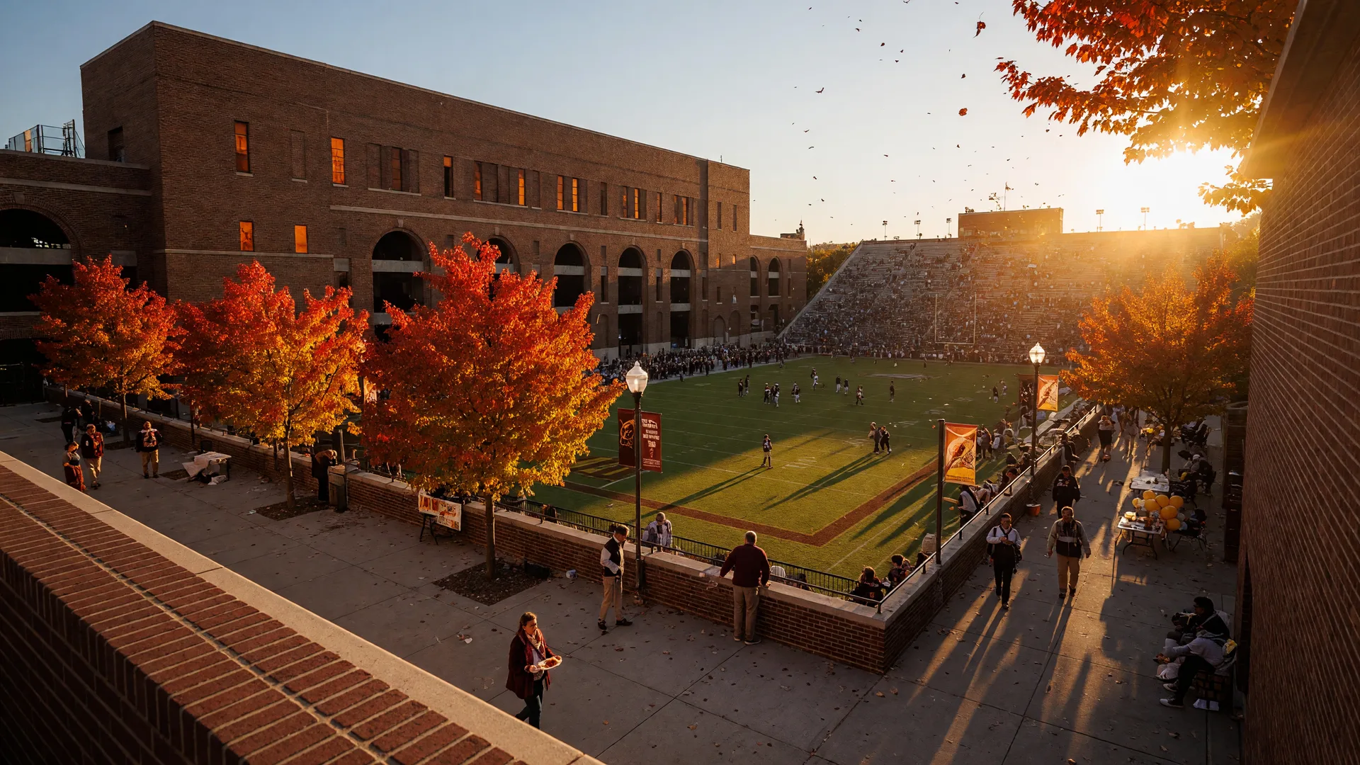 Historic brick college football stadium on Howard University's campus in Washington DC on a golden mid-October afternoon, red and gold autumn maples around the concourse, distant crowds in the stands, and fall banners ahead of homecoming weekend