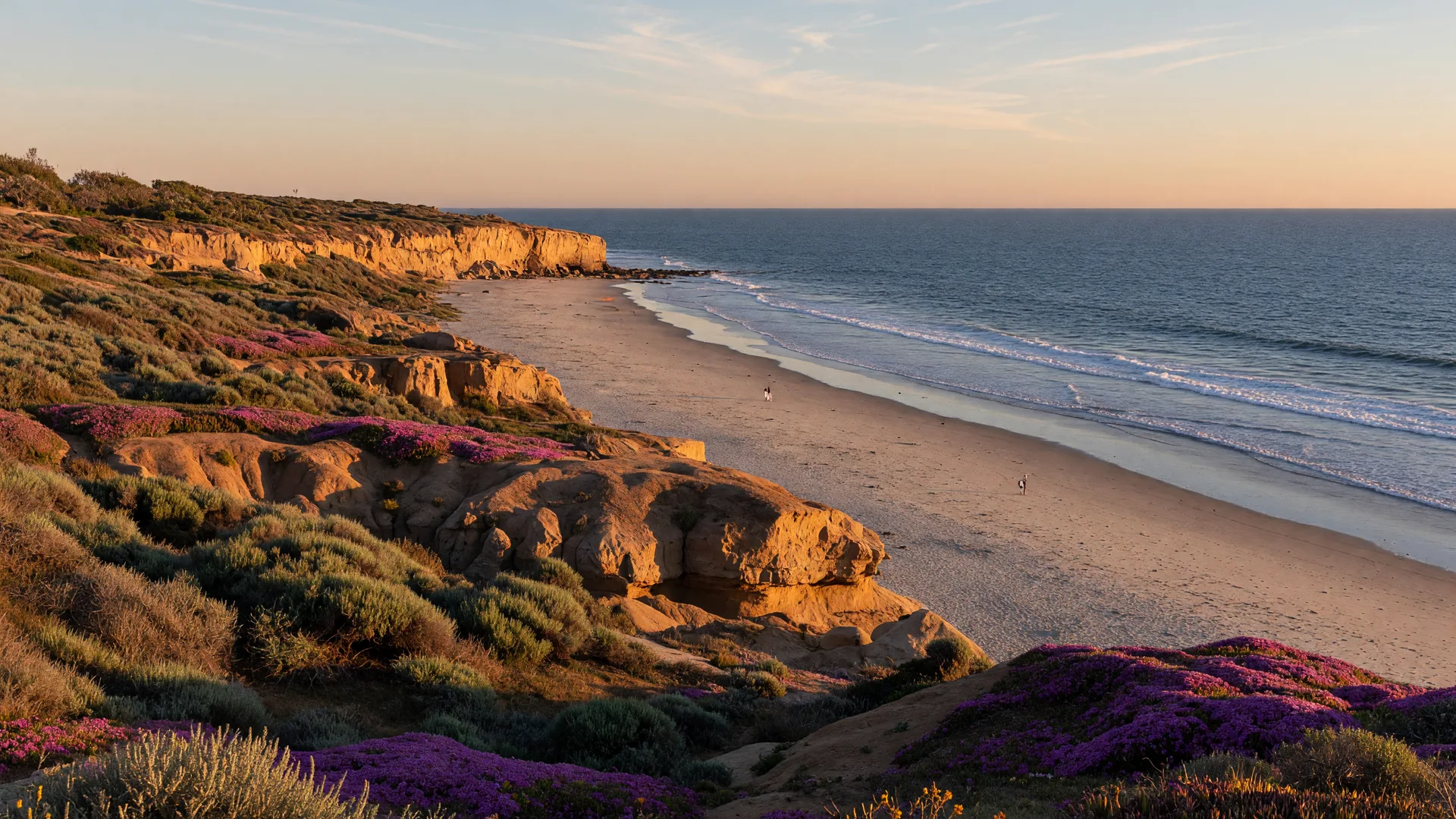 Low coastal bluffs above a wide sandy beach with the Pacific stretching to the horizon at golden hour, the kind of coastline Del Mar is known for
