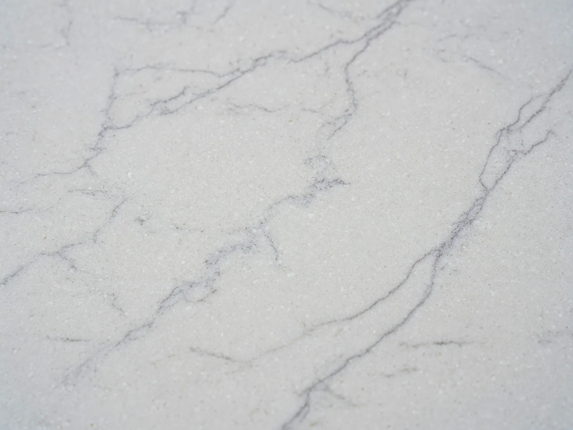 Macro texture of a white quartz countertop with subtle grey veining