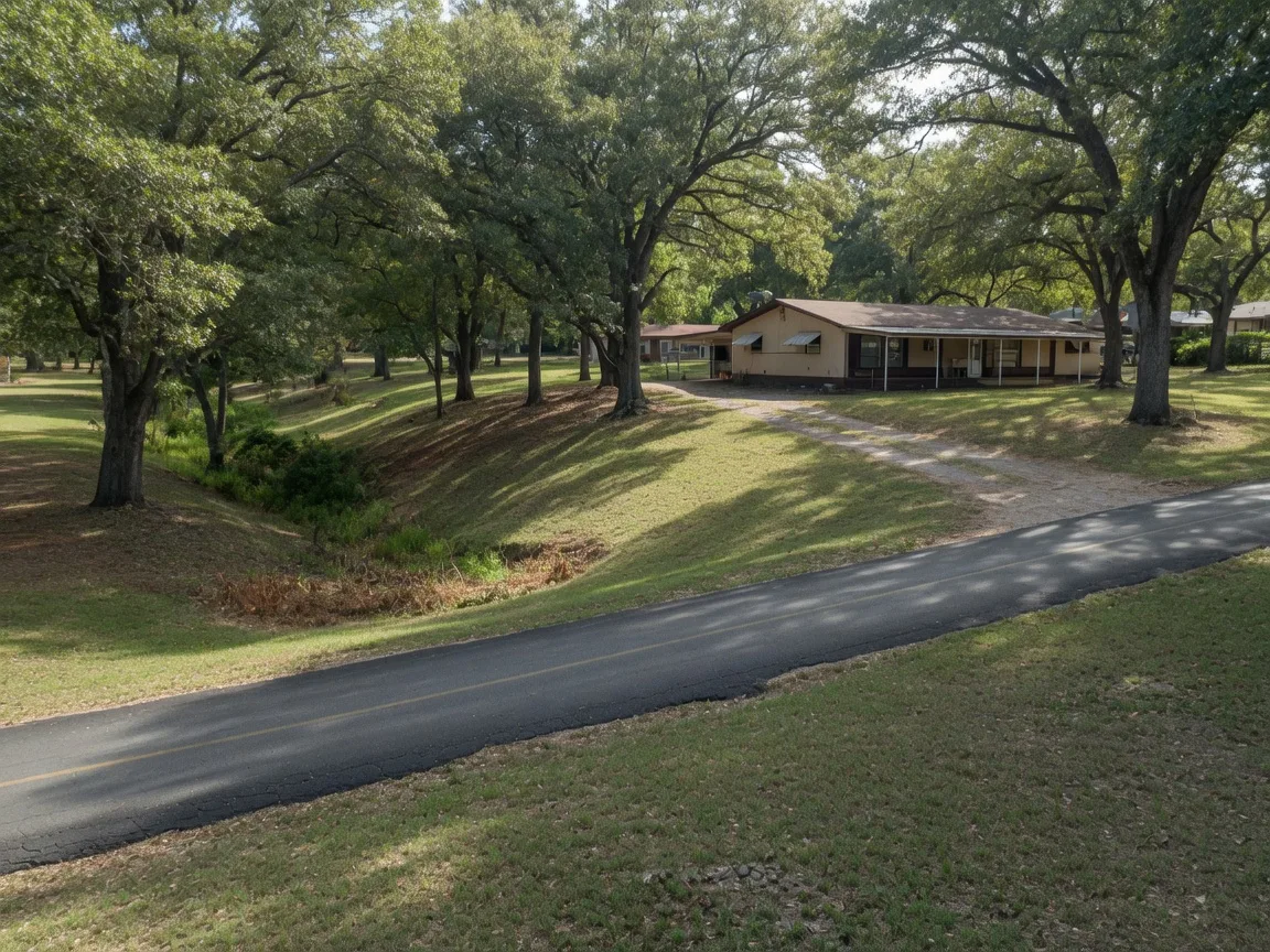 A large oak-shaded residential lot on a narrow street without curb or gutter in West of West Castle Hills