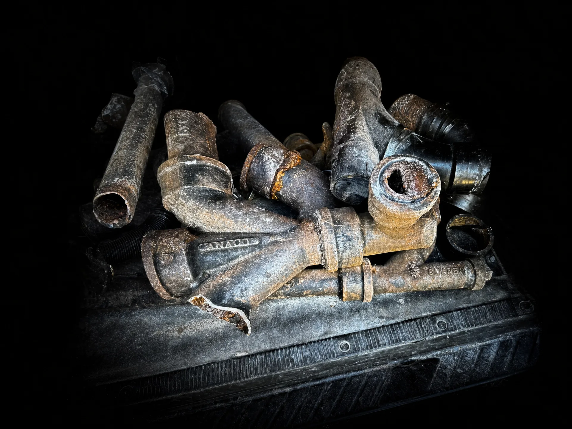 Old, corroded cast-iron plumbing pipes being cut out of a wall during a whole-home repipe