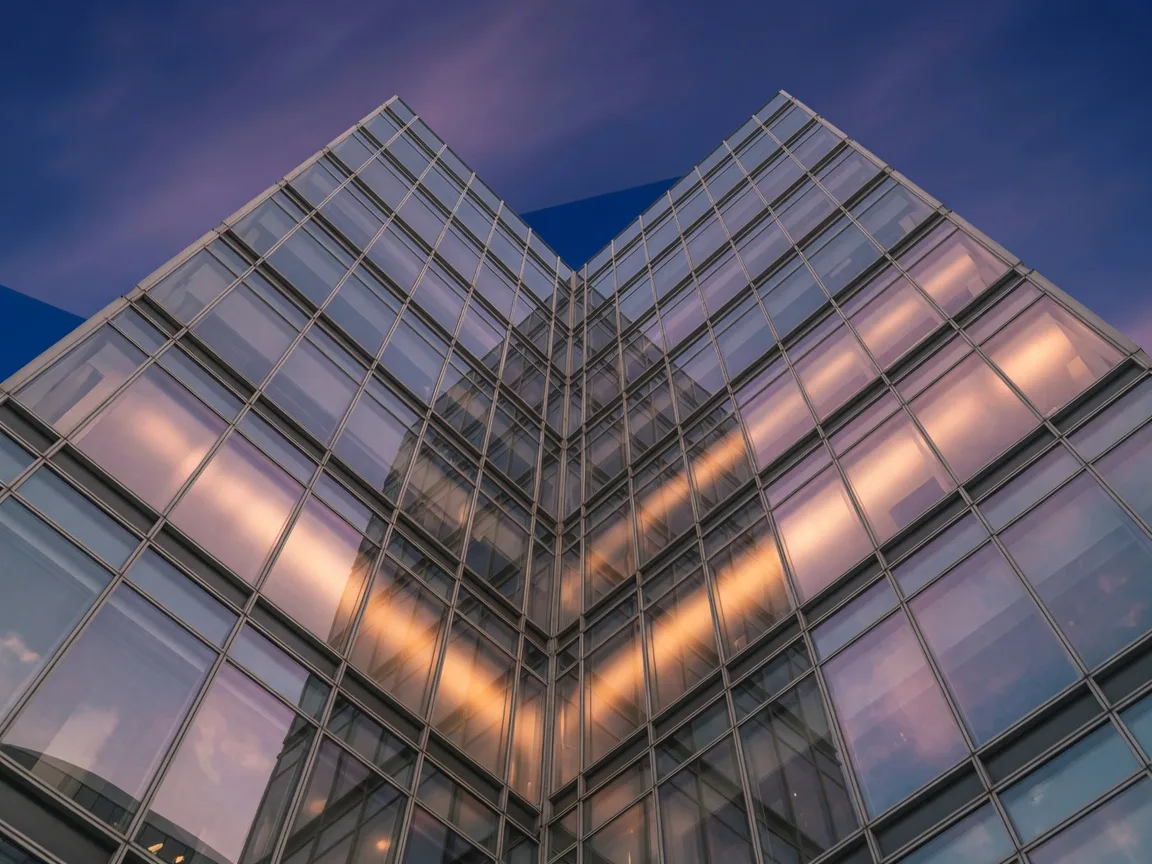 A modern glass office tower with warm gold reflections