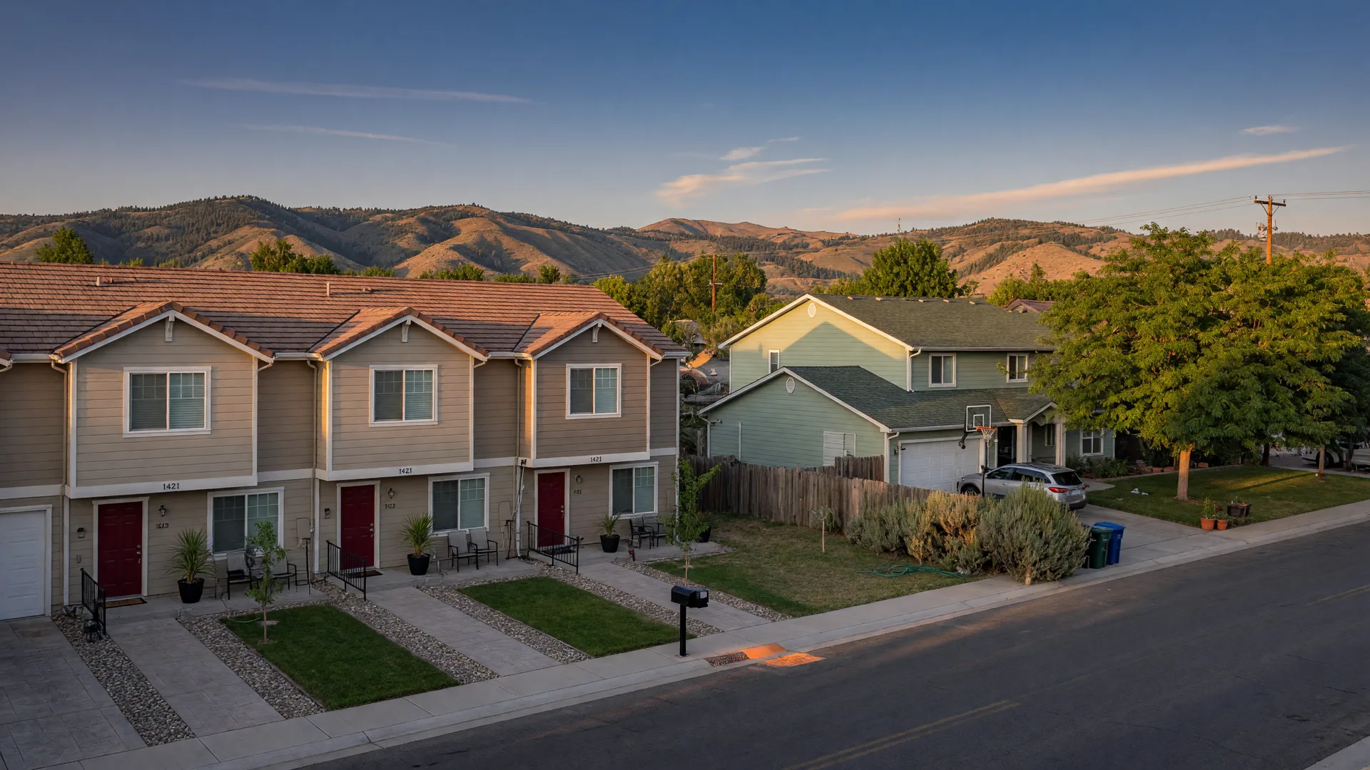 A quiet residential street in the Boise area with a row of attached townhomes beside a detached single-family home at golden hour
