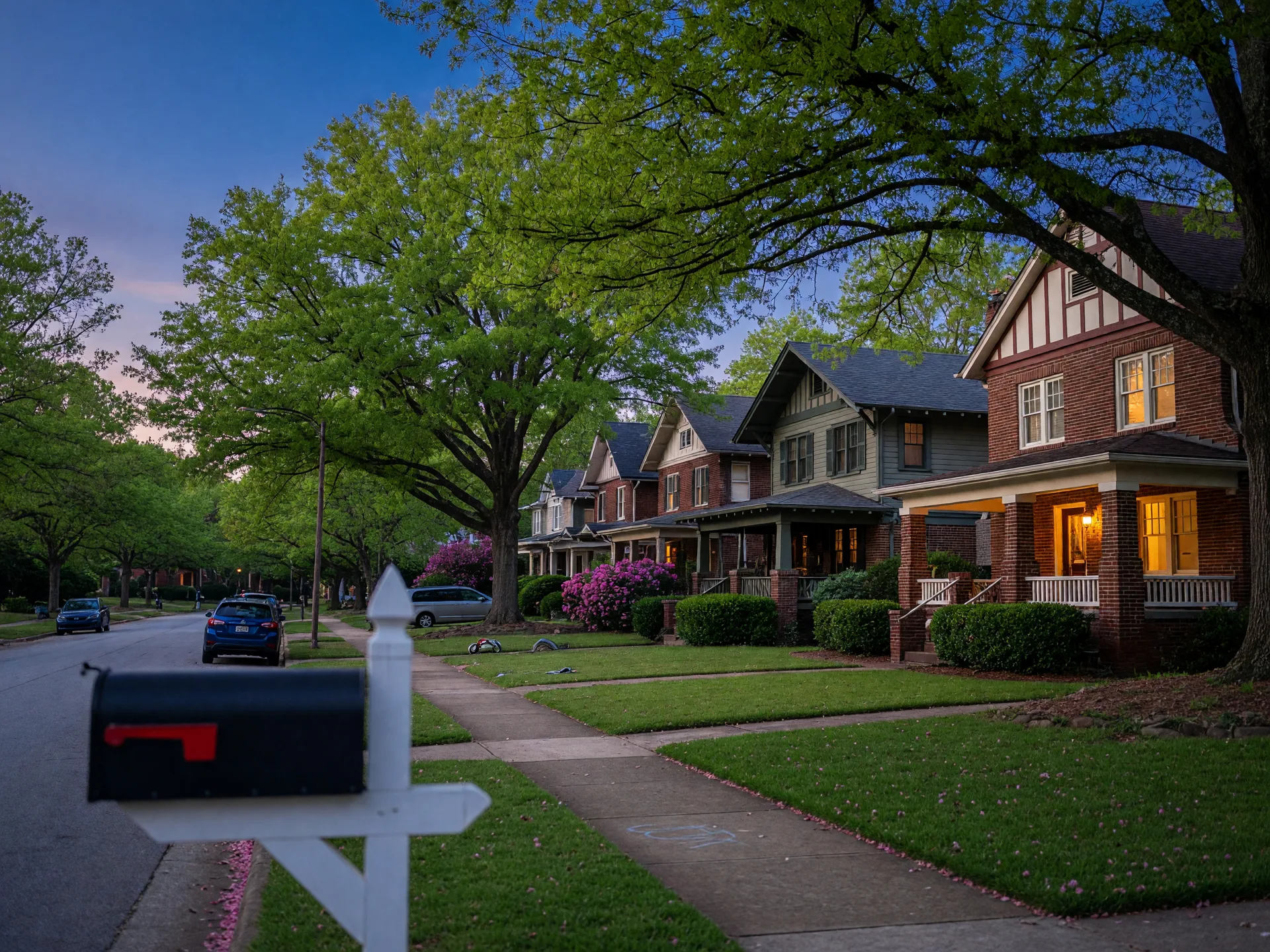 A tree-lined residential street of brick and craftsman homes in a Metro Atlanta suburb at dusk