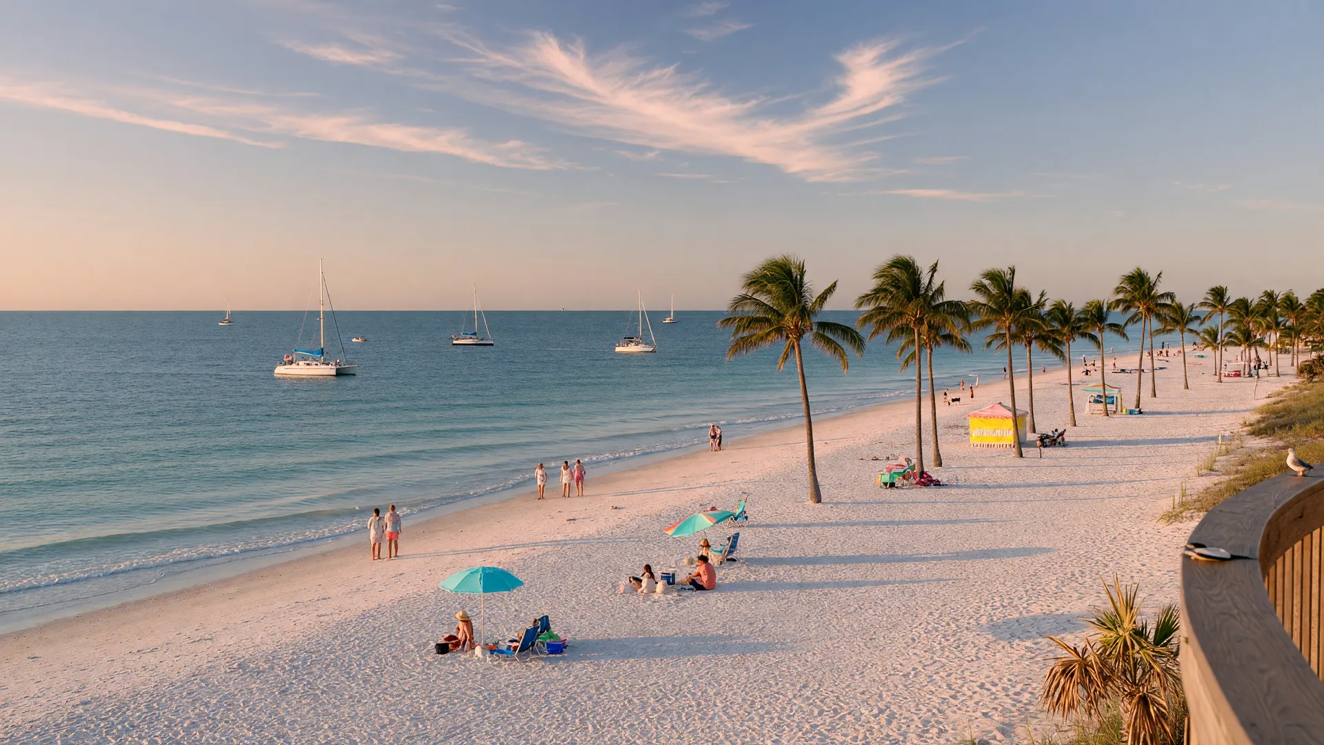 Siesta Key Beach during peak season with turquoise Gulf waters, white quartz sand, and sailboats in the distance under afternoon sunlight