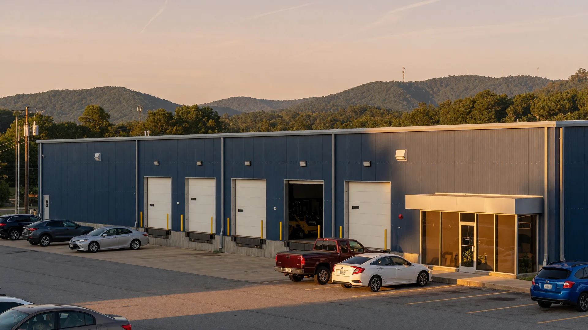 A modern high-tech manufacturing facility with loading bays set against rolling foothills in Oakwood, Georgia, in golden-hour light