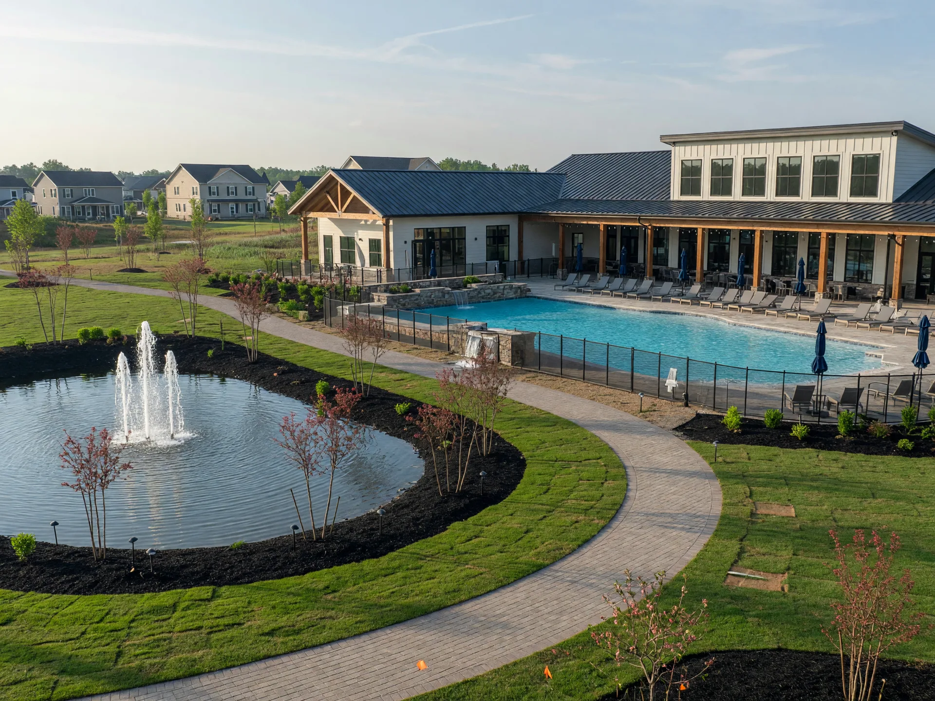A new community amenity center in the Upstate with a clubhouse, pool, and a walking trail beside a landscaped pond