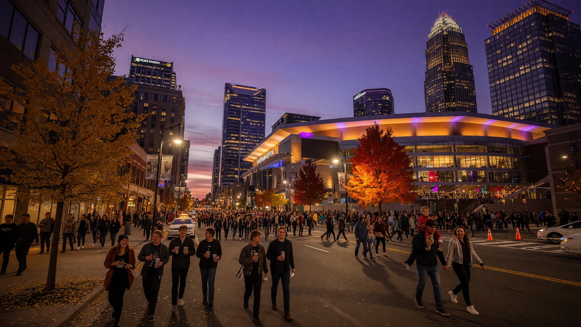 Autumn evening on South Tryon Street in Uptown Charlotte with people heading toward Spectrum Center beneath a twilight sky