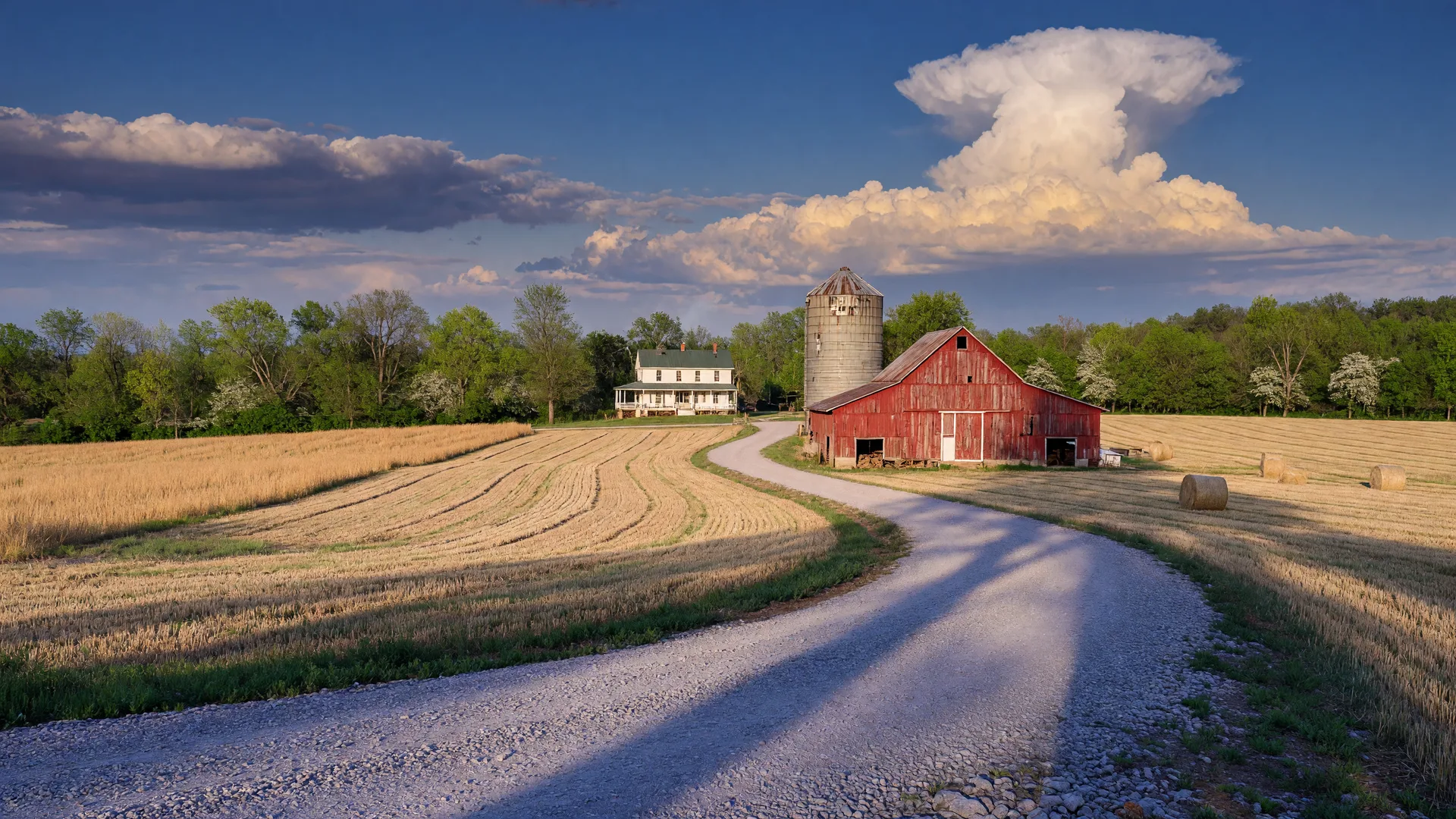 A gravel farm lane curving toward a red barn and white farmhouse in rural Warren County