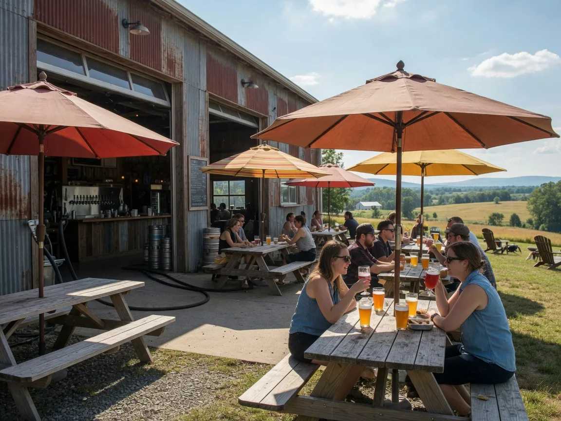 A craft brewery taproom with outdoor picnic tables and umbrellas, rustic industrial building open to the Virginia countryside
