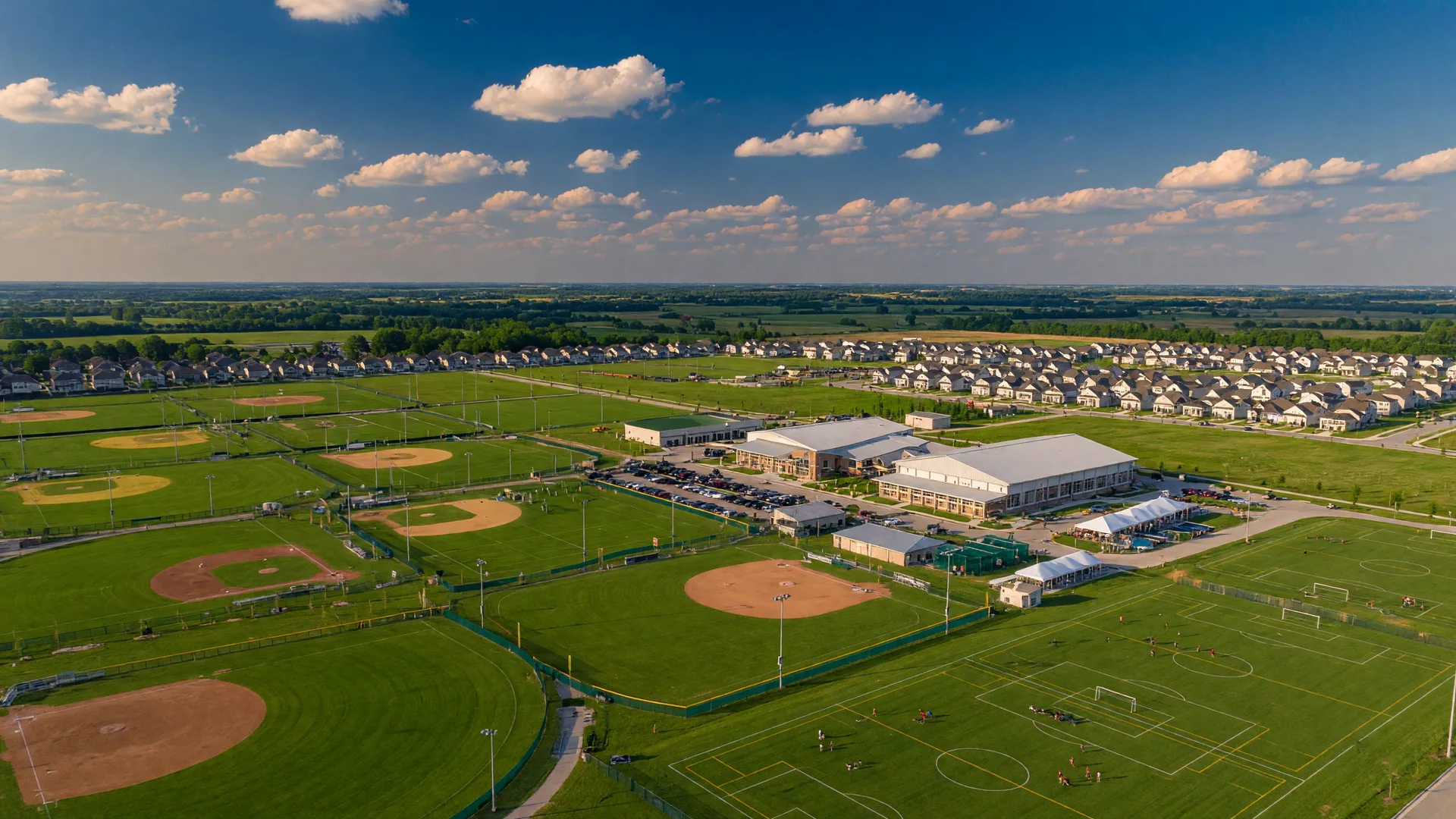Grand Park Sports Campus in Westfield, Indiana with athletic fields and new traditional homes in the background under a bright blue sky