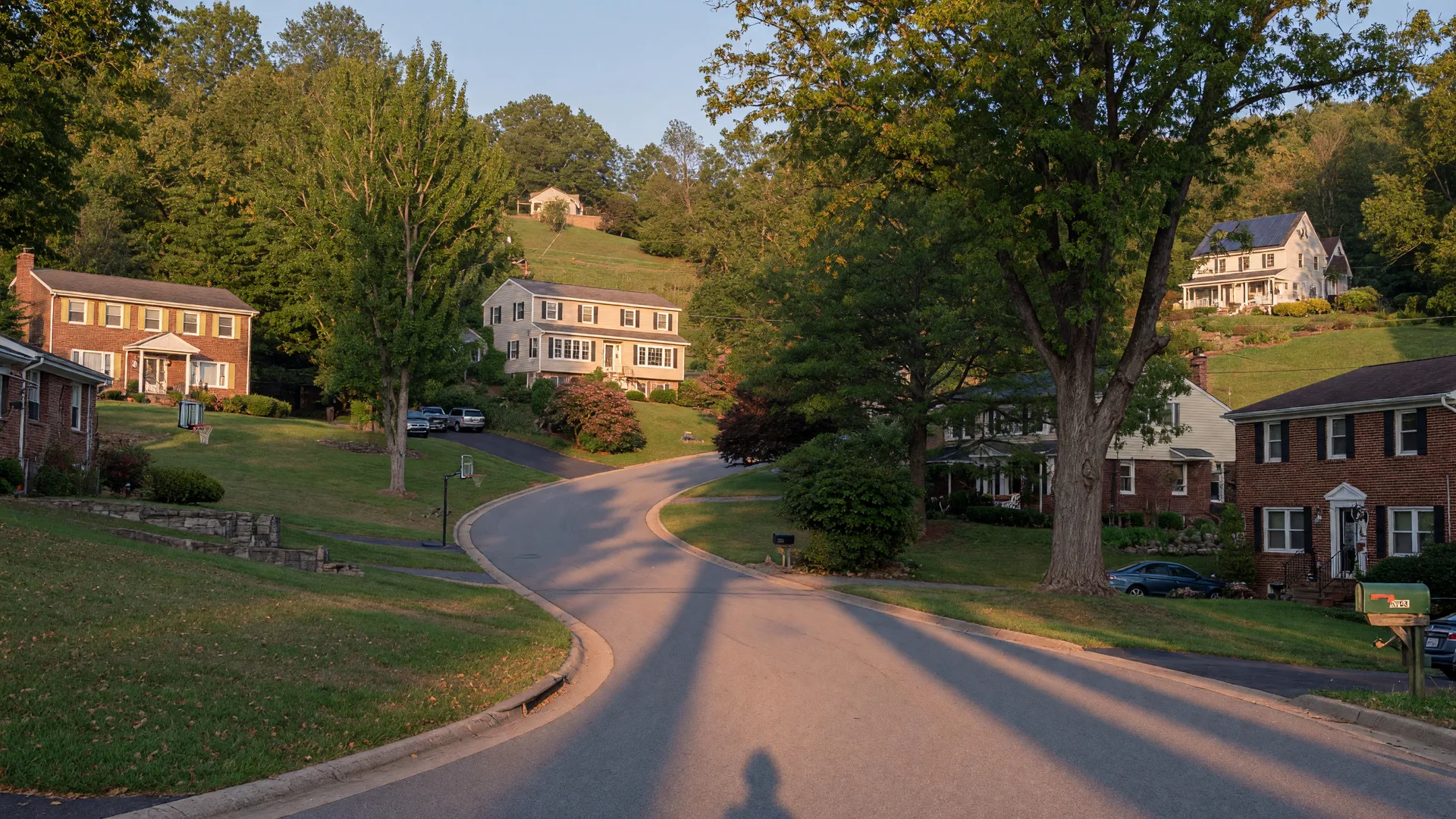 A winding residential street of single-family homes in Ellicott City, Howard County Maryland in golden late-day light
