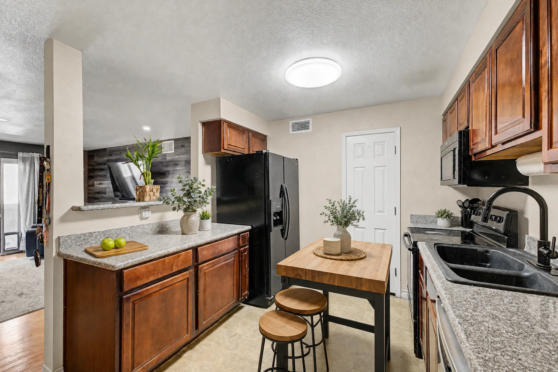 Virtually staged kitchen with wood cabinetry and a breakfast bar at 2451 Rainbow Blvd Unit 2122