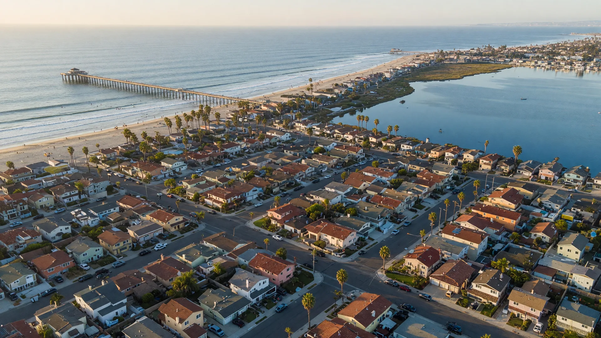 Aerial view of the coastal residential streets of Imperial Beach, CA 91932, with red-tile-roof beach homes between the Pacific Ocean and the bay on a late-September afternoon