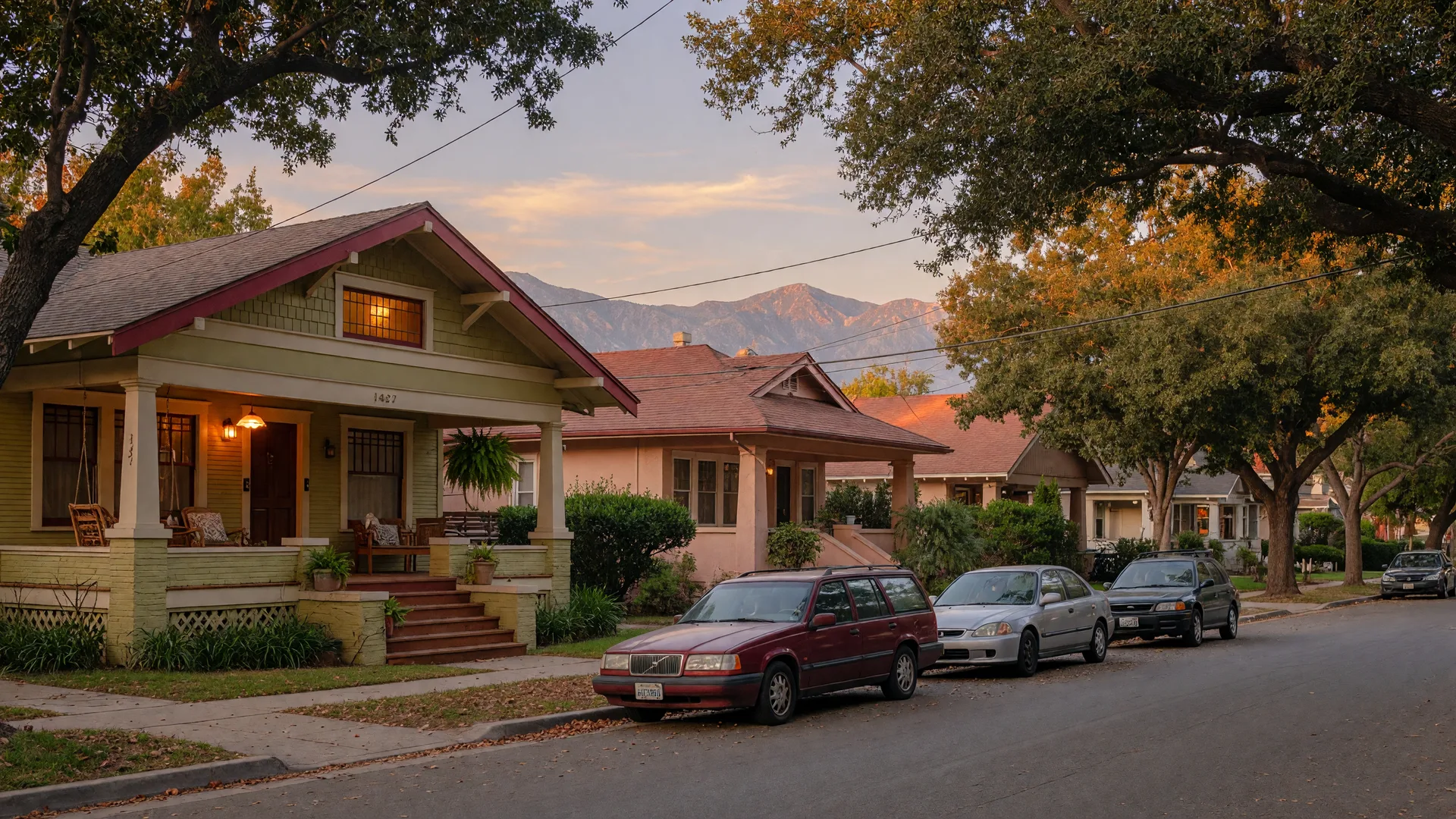 A warm tree-lined Pasadena Craftsman street at golden hour with porch lights glowing and the San Gabriel Mountains beyond