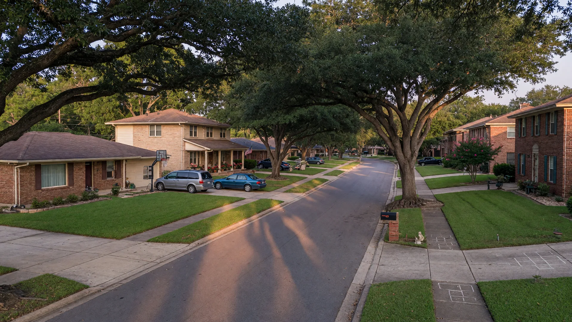 An established North San Antonio Hills street with 1980s and 1990s brick ranch and two-story homes under mature shade trees at late afternoon, in the San Antonio home inspection service area of Rodeo Home Inspections