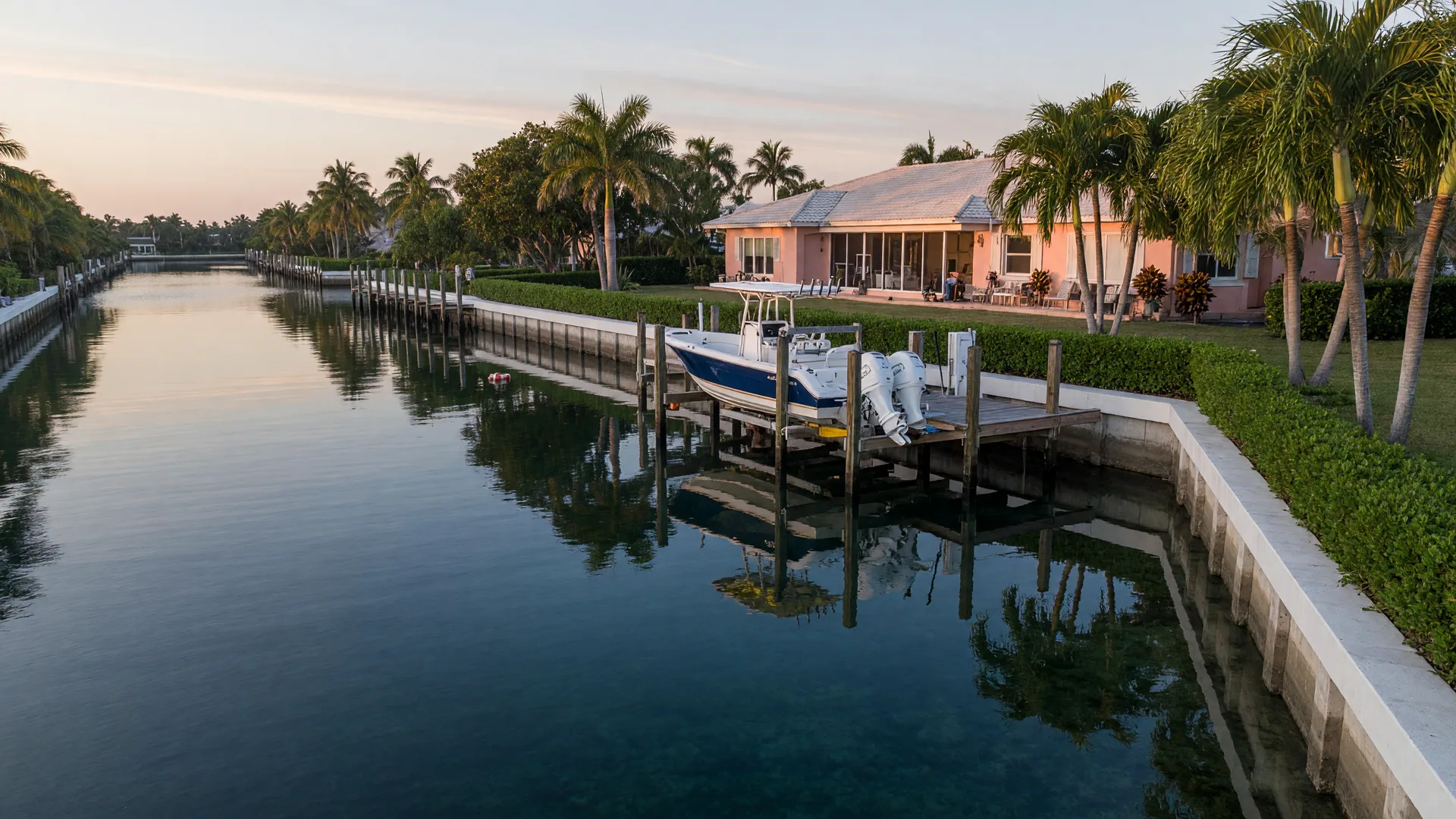 A South Florida waterfront home with a boat dock and lift above a calm, deep canal