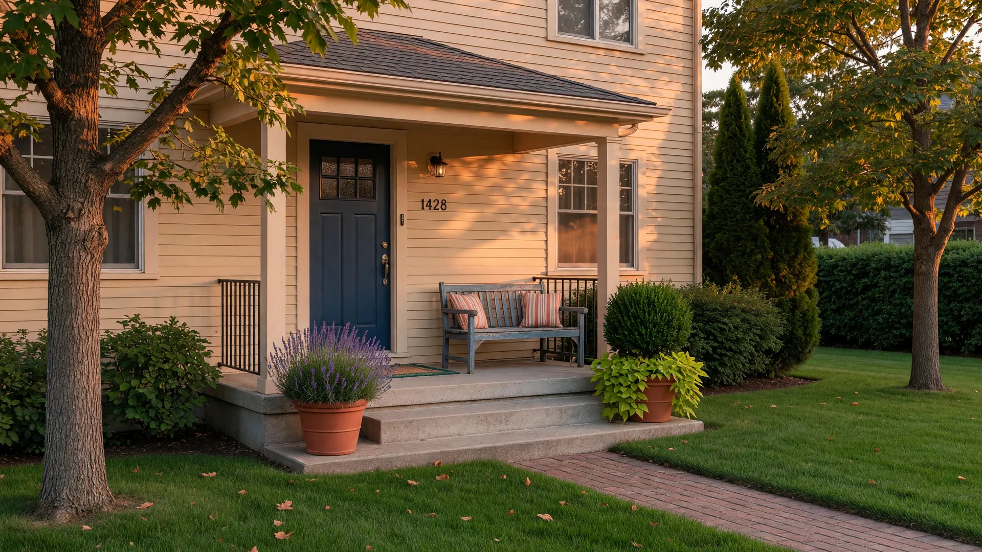 A quiet family home's front porch at golden hour with potted plants and a bench beside a solid front door