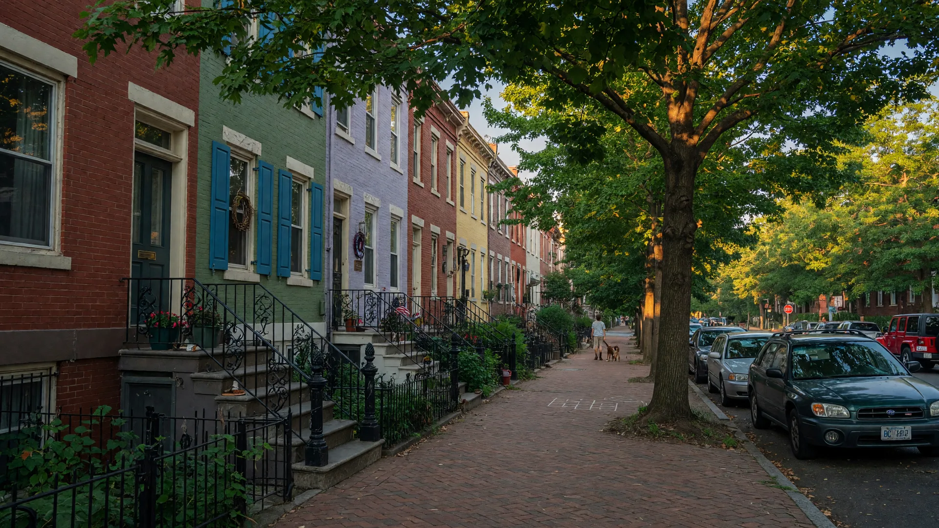 Historic brick rowhouses on a tree-lined street in Washington DC's Capitol Hill neighborhood at golden hour, with brick sidewalks and colorful front doors