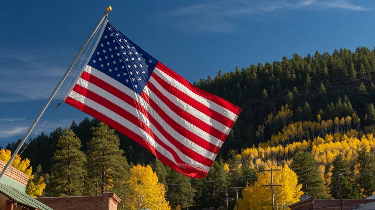 An American flag flying against a deep blue October sky with golden aspens and Ponderosa pines on the Mogollon Rim behind it