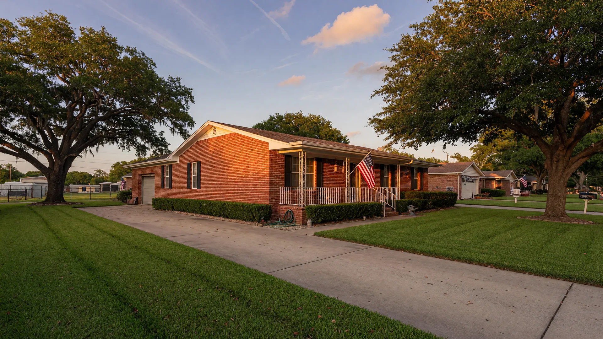 Brick Texas Hill Country home at golden hour with a small US flag beside the front porch