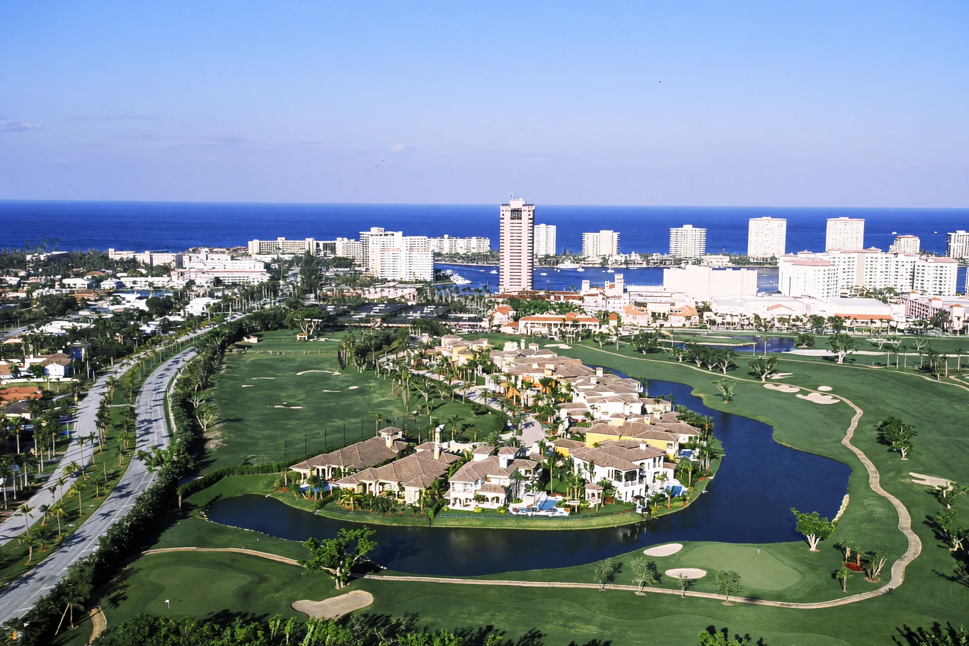 Aerial view of Boca Raton luxury homes along a golf course with the coastal skyline and ocean beyond