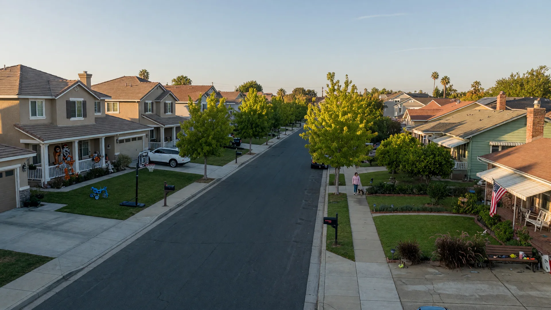 A tree-lined Elk Grove street with newer tract homes and an older established pocket