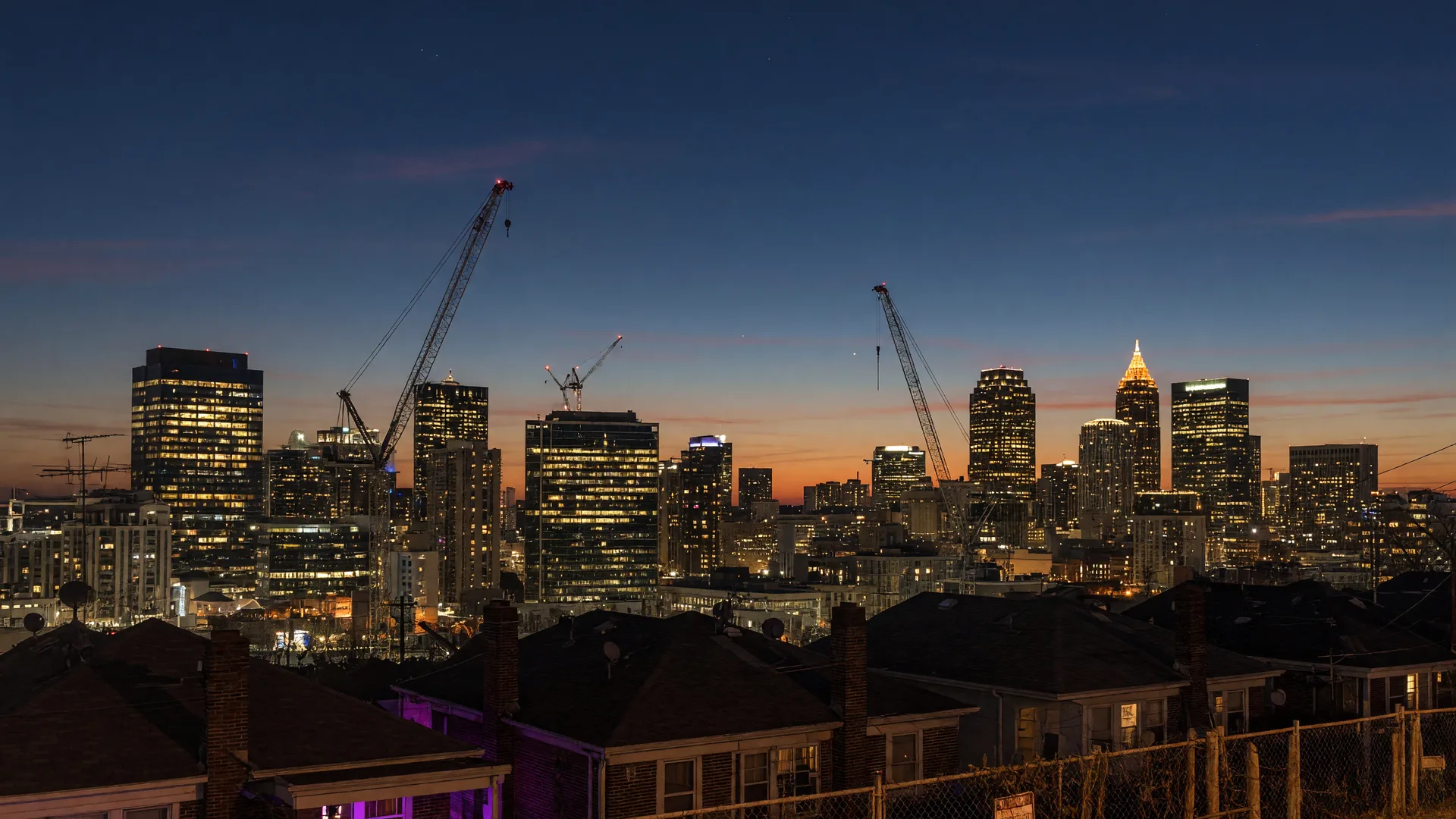 Atlanta downtown commercial skyline at dusk with glowing office towers and construction cranes