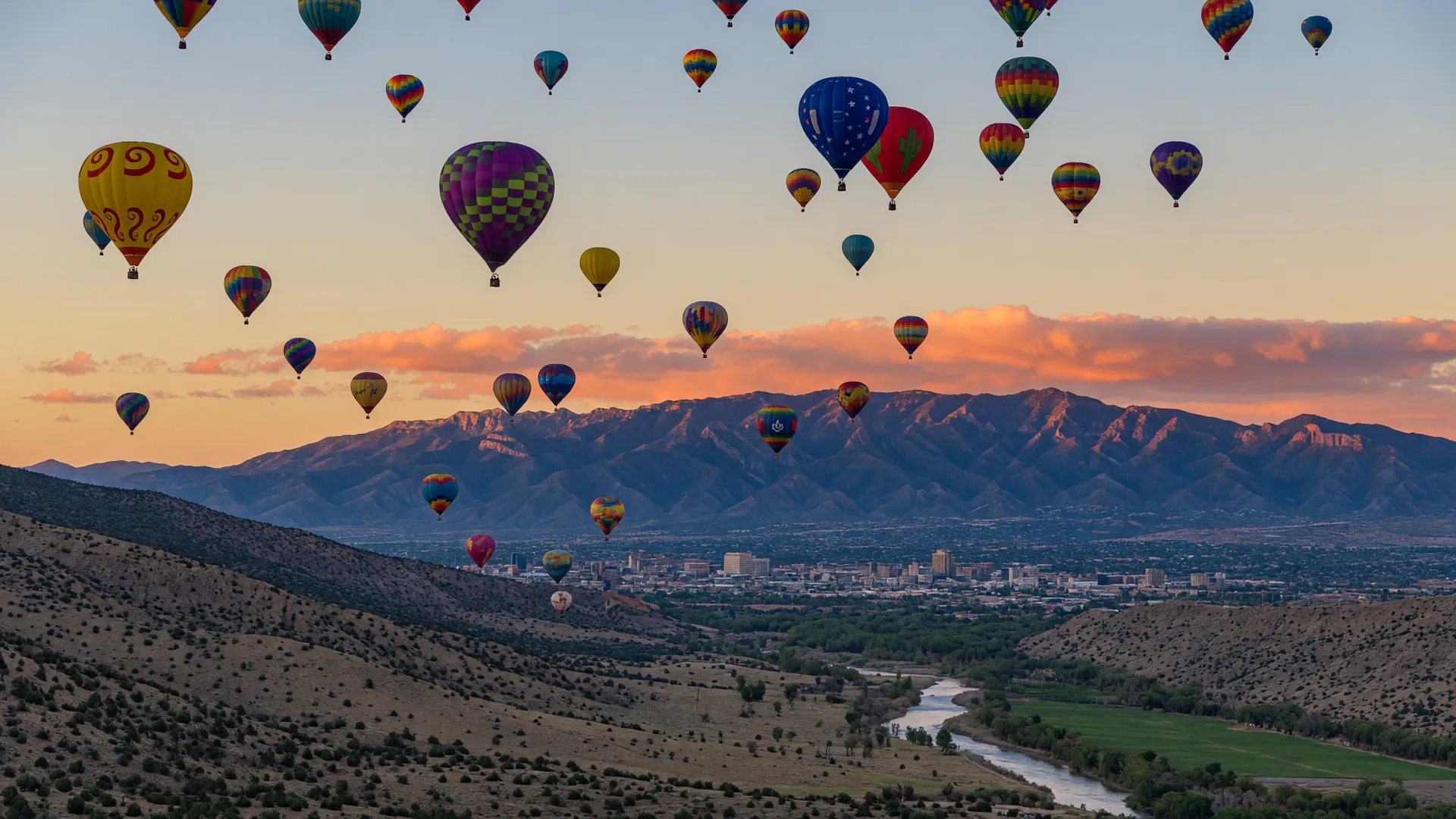 Colorful hot air balloons rising over the Rio Grande valley at sunrise with the Sandia Mountains glowing in the background