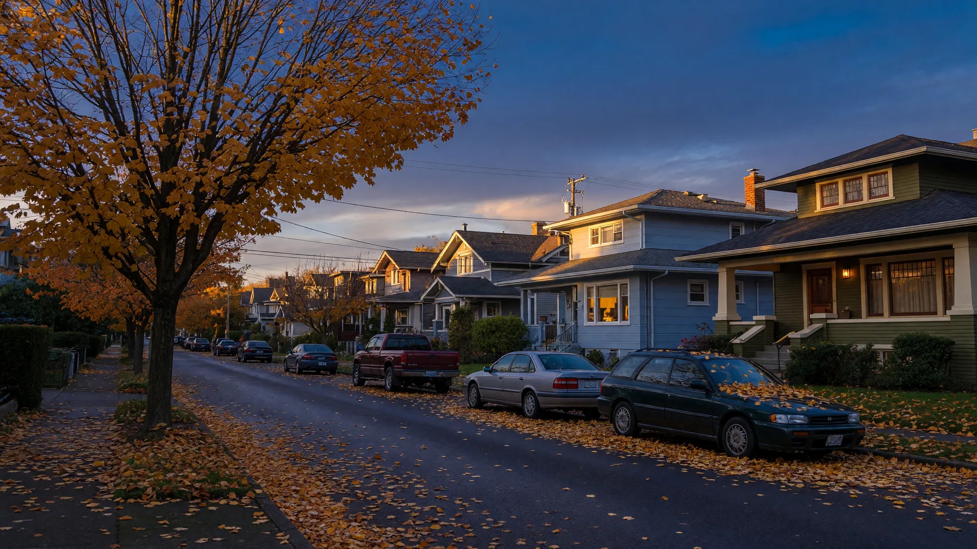 A quiet Pacific Northwest residential street in early October with autumn leaves and warm evening light