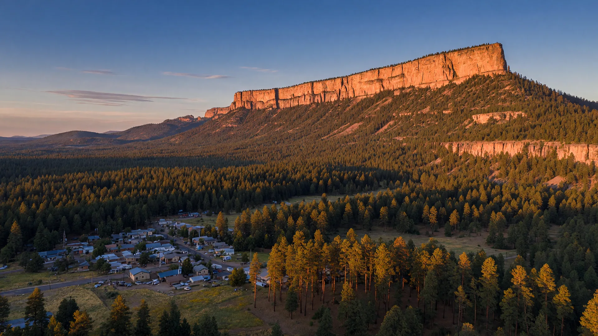 Golden hour aerial view of Arizona's Rim Country with Ponderosa pine forest rolling toward the Mogollon Rim escarpment at sunset