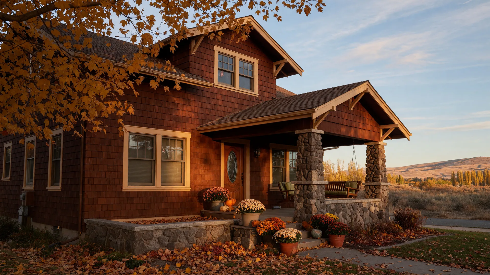 A warm craftsman home in the Tri-Cities with cedar siding and stone porch columns in golden mid-October light, autumn leaves turning