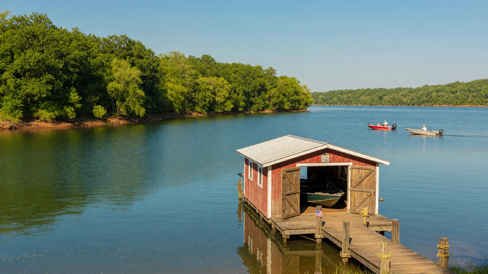A wooden dock and boathouse on a calm cove of Barren River Lake in South Central Kentucky on a summer afternoon