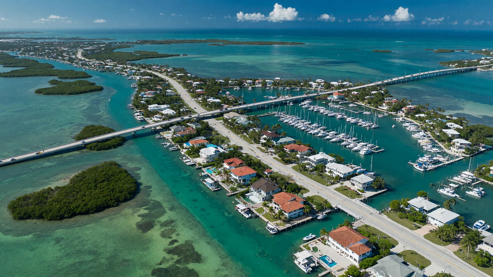 Aerial view of the Florida Keys island chain with turquoise water, the Overseas Highway, and waterfront homes on a bright August morning