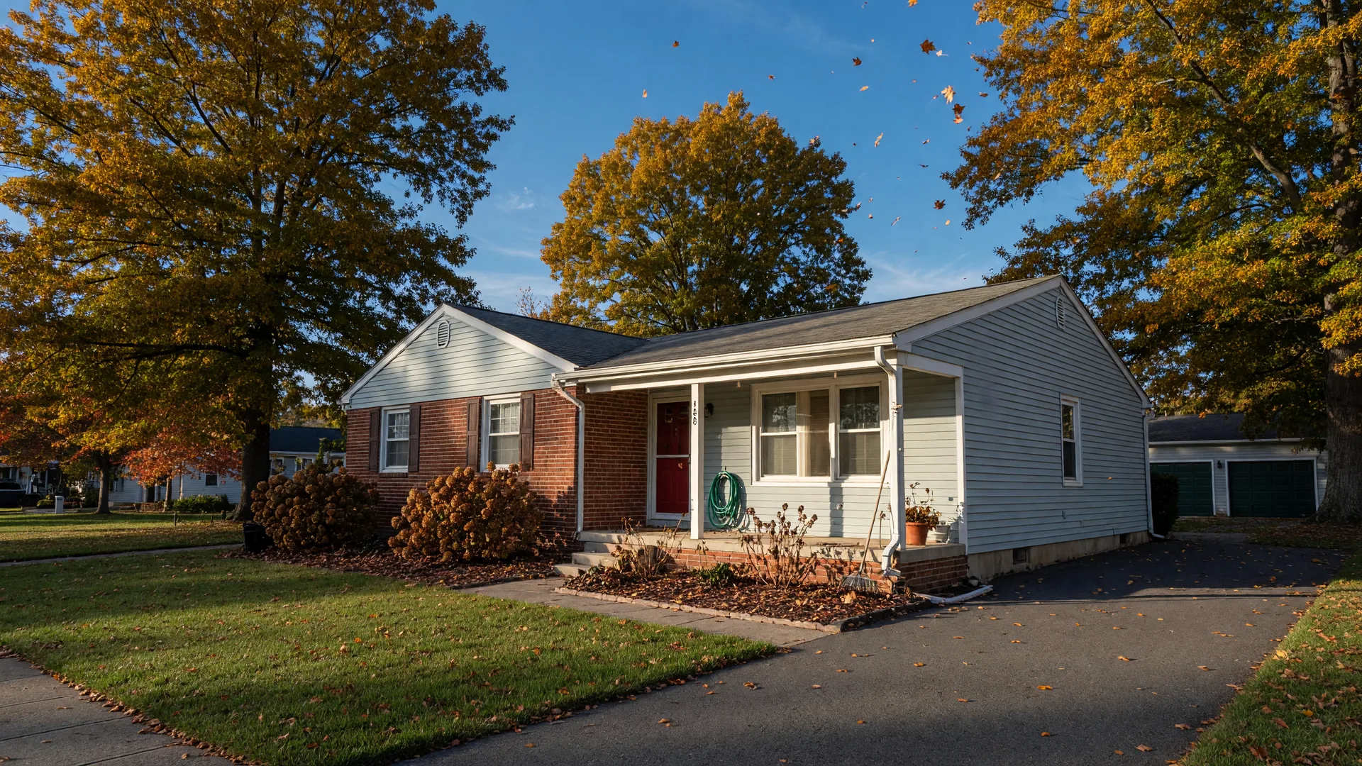Single-family Virginia Beach home in October with oak trees dropping gold and amber leaves across the front lawn in crisp fall light