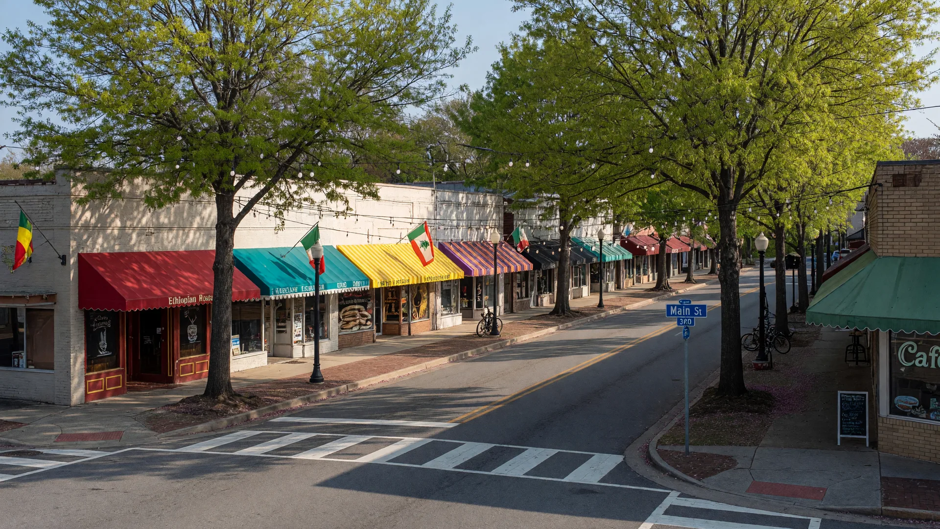 Downtown Clarkston Georgia main street with international restaurant storefronts, colored awnings, and mature oak trees