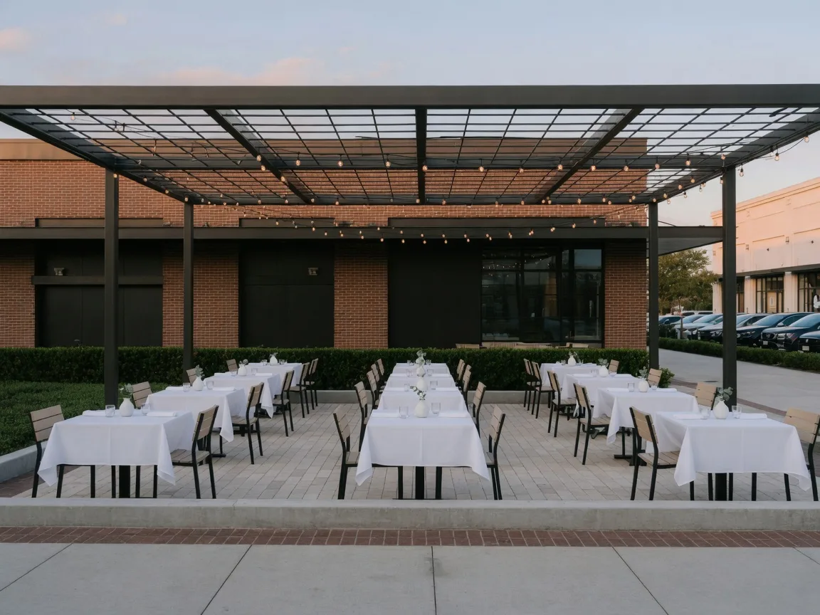 A clean restaurant patio with tables under a pergola in a Texas shopping district