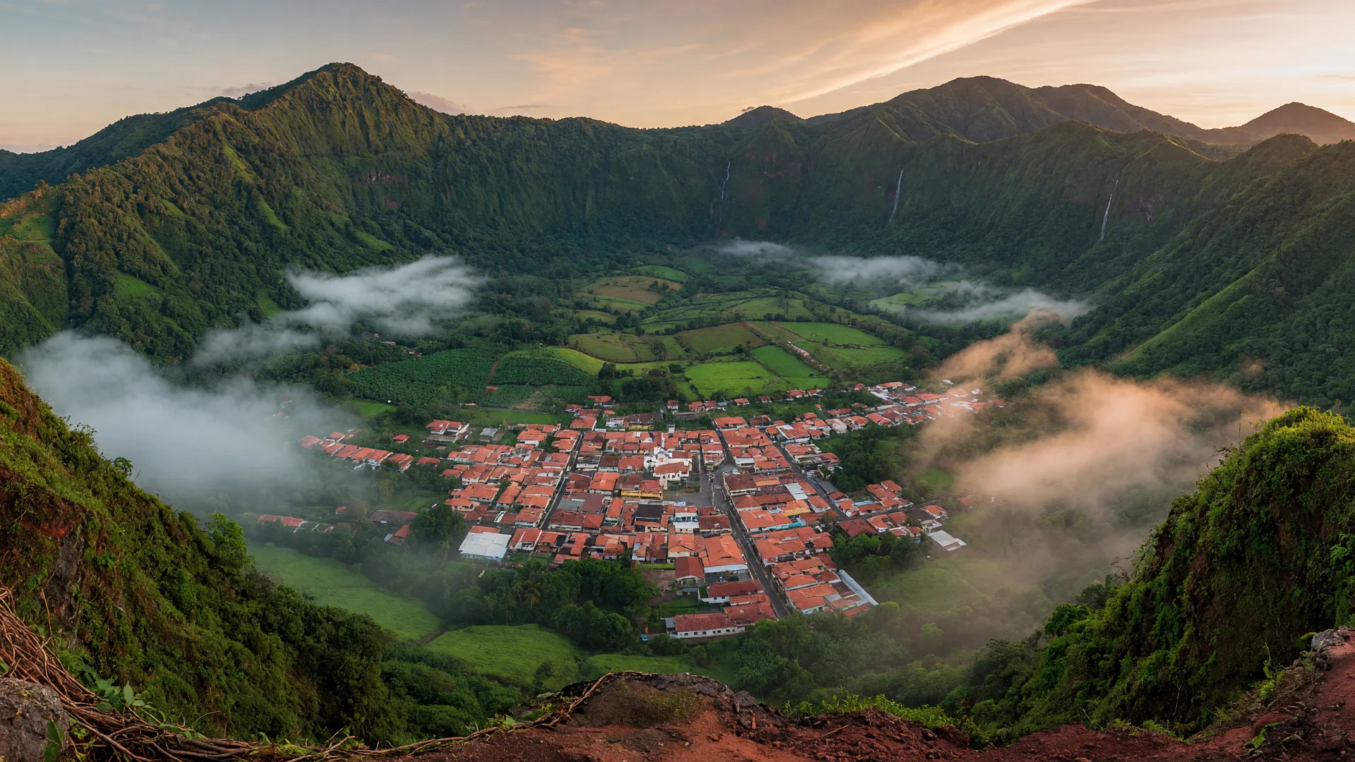 The green volcanic crater valley of El Valle de Antón, Panama, with the town below and forested ridges in morning mist