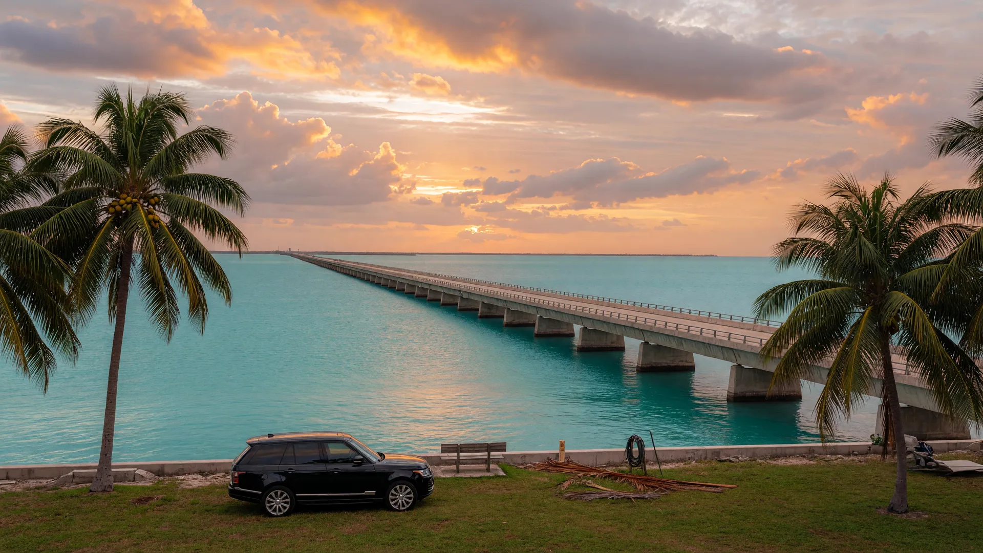 The Seven Mile Bridge in Marathon at golden hour framed by coconut palms with turquoise water