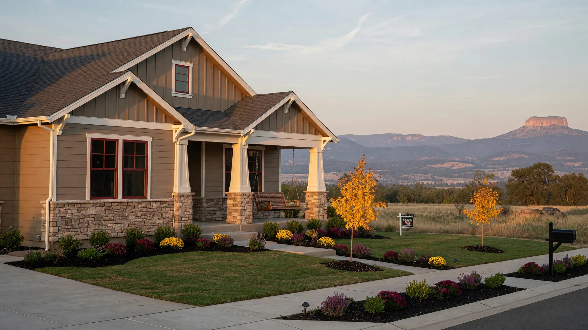 A brand-new craftsman-style home in a Southern Oregon subdivision at golden hour, with warm siding and Rogue Valley foothills in the distance