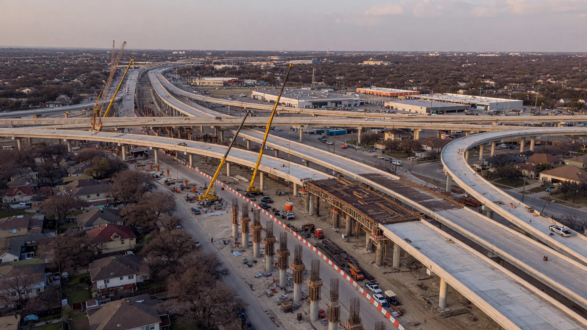 Elevated highway and interchange lanes under construction over suburban neighborhoods in the northeast San Antonio corridor