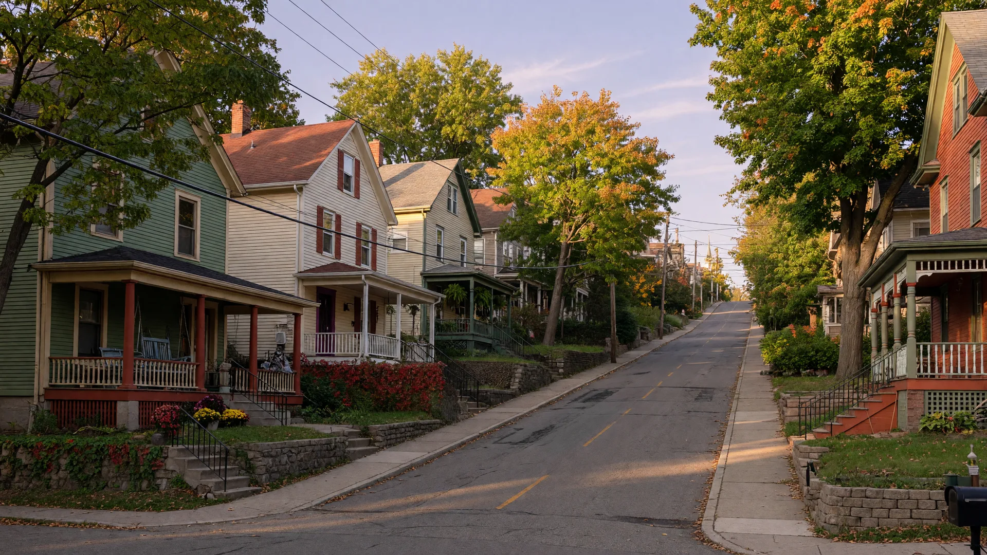 A steep tree-lined street in the Water Hill neighborhood of Ann Arbor with colorful Victorian and Cape Cod homes