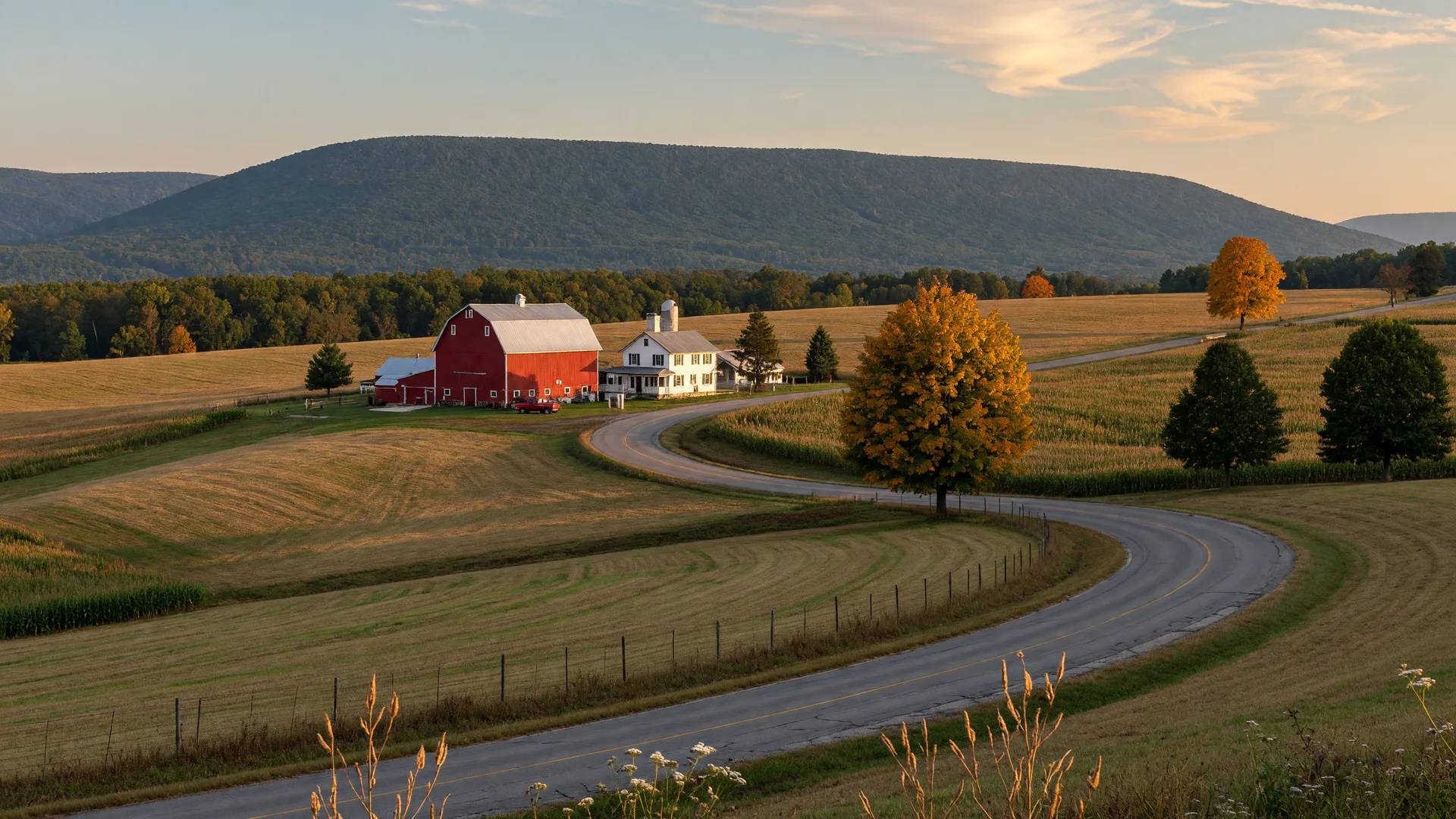 A curving rural Lehigh County road in early-autumn color with a red barn and the Blue Mountain ridge on the horizon