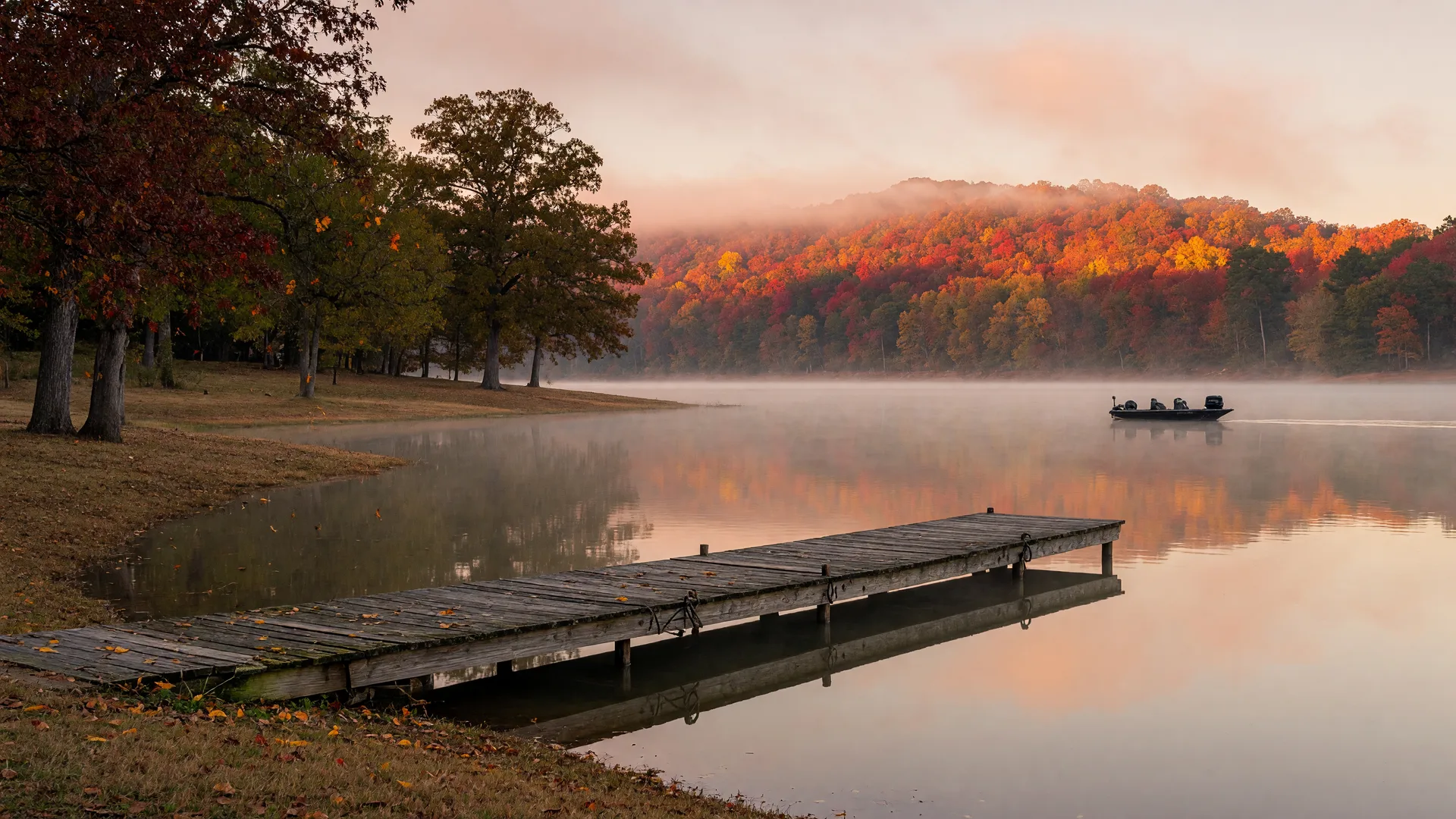 A calm Lake Hartwell cove at late-October dawn with mist over the water, a wooden dock at the shoreline, and a distant boat silhouette