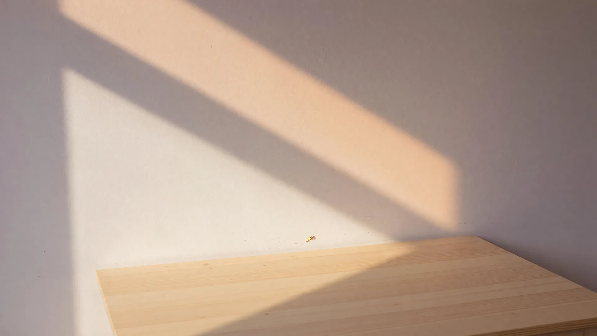 Soft daylight on a warm white wall and light wood