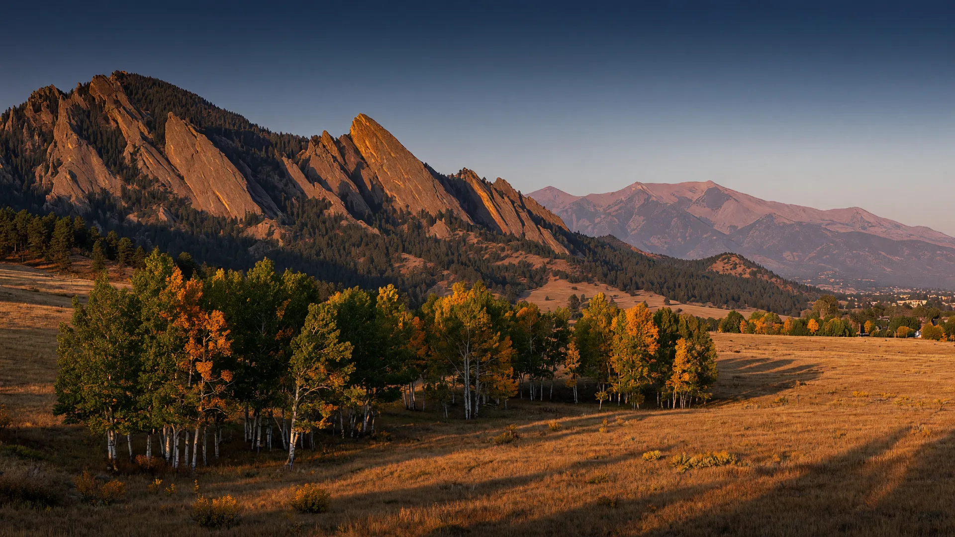 Early fall golden light over the Flatirons with turning aspens in Boulder Colorado